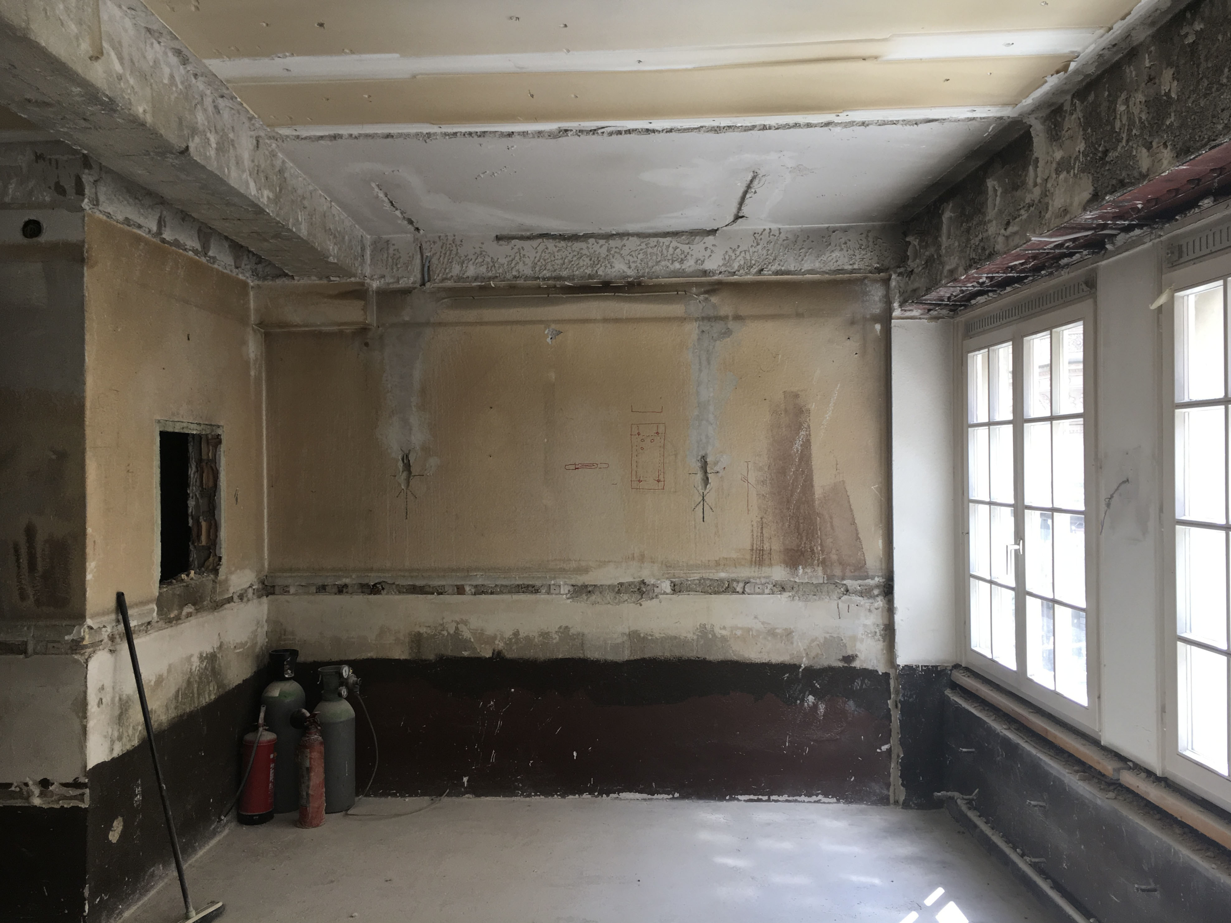 Apartment 8 before — stripped wall with layout sketches. The opening will become the sleeping nook.