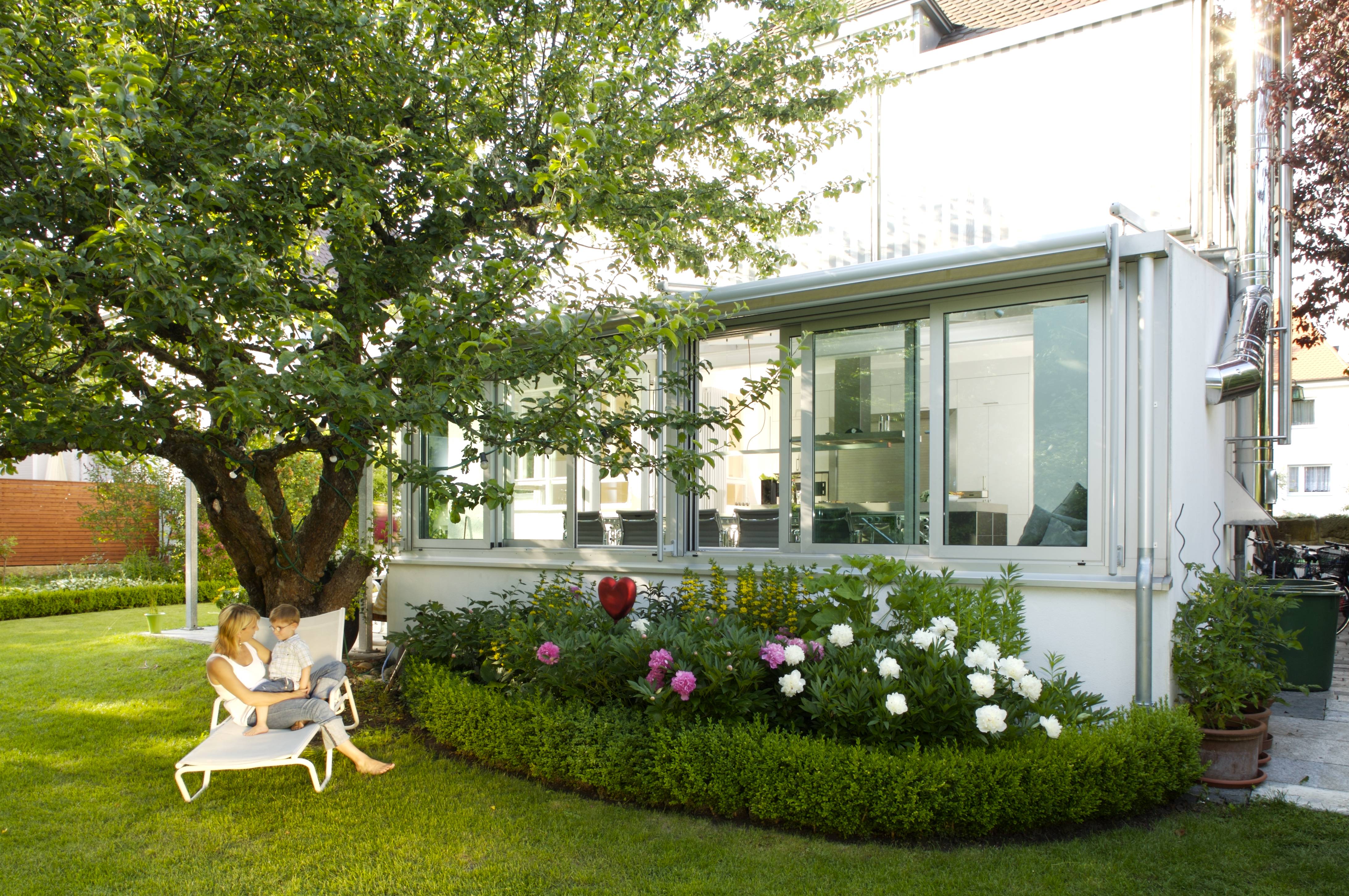 The addition seen from the garden — aluminum frame and glass, planted border of box and peonies
