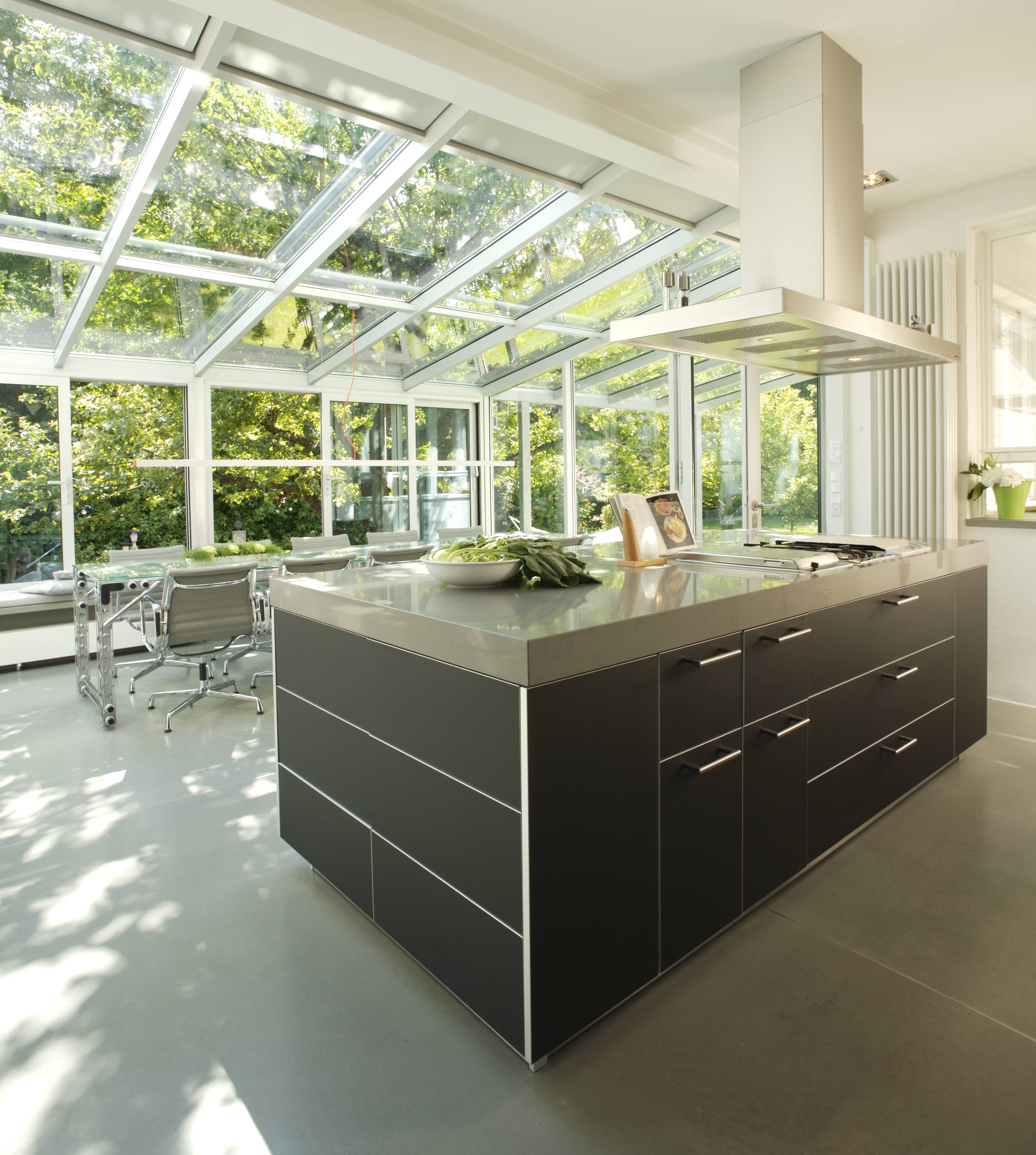 Kitchen island — dark fronts, solid surface worktop, glass roof and garden beyond