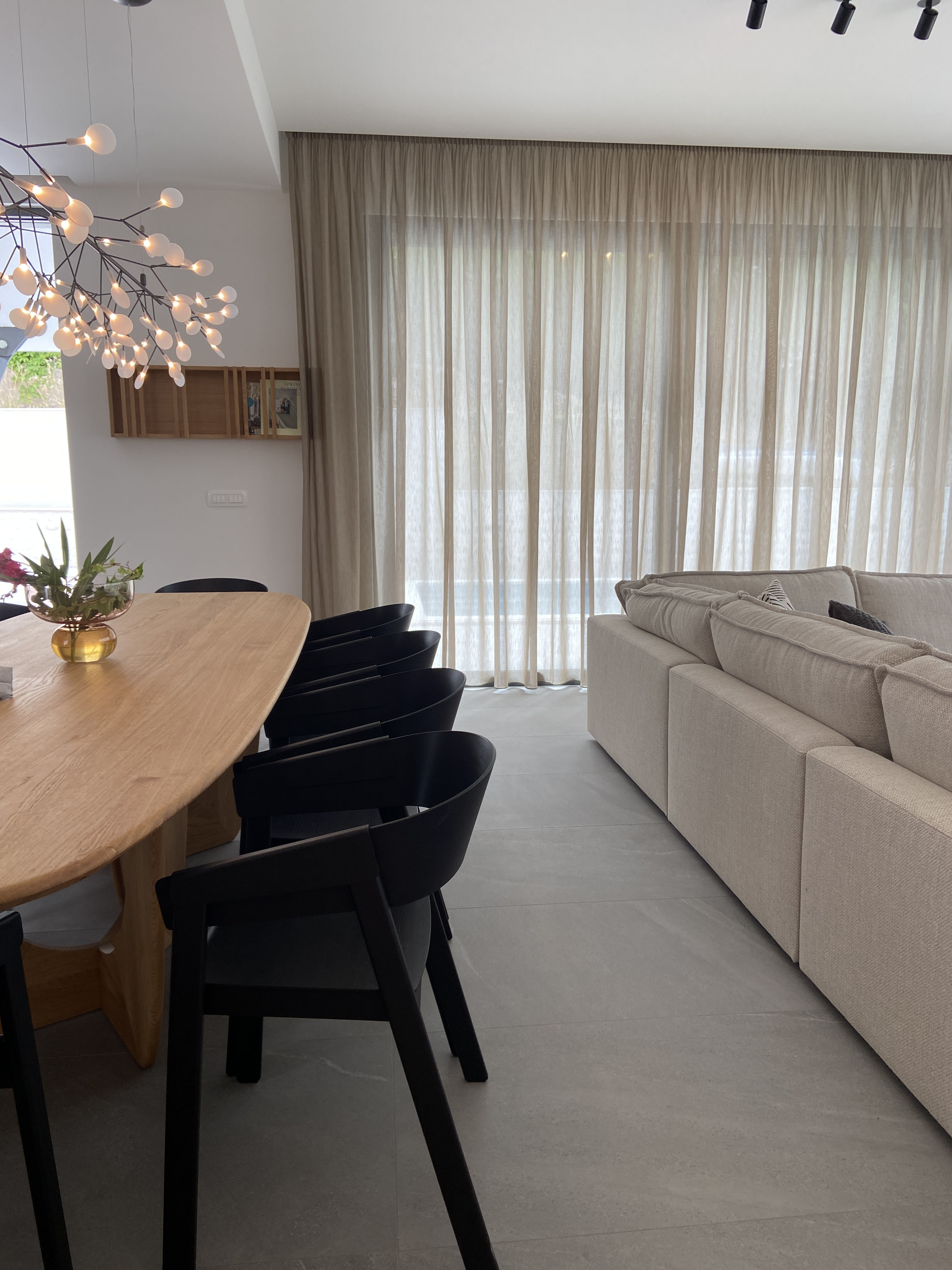 Dining area with sculptural chandelier and living space beyond