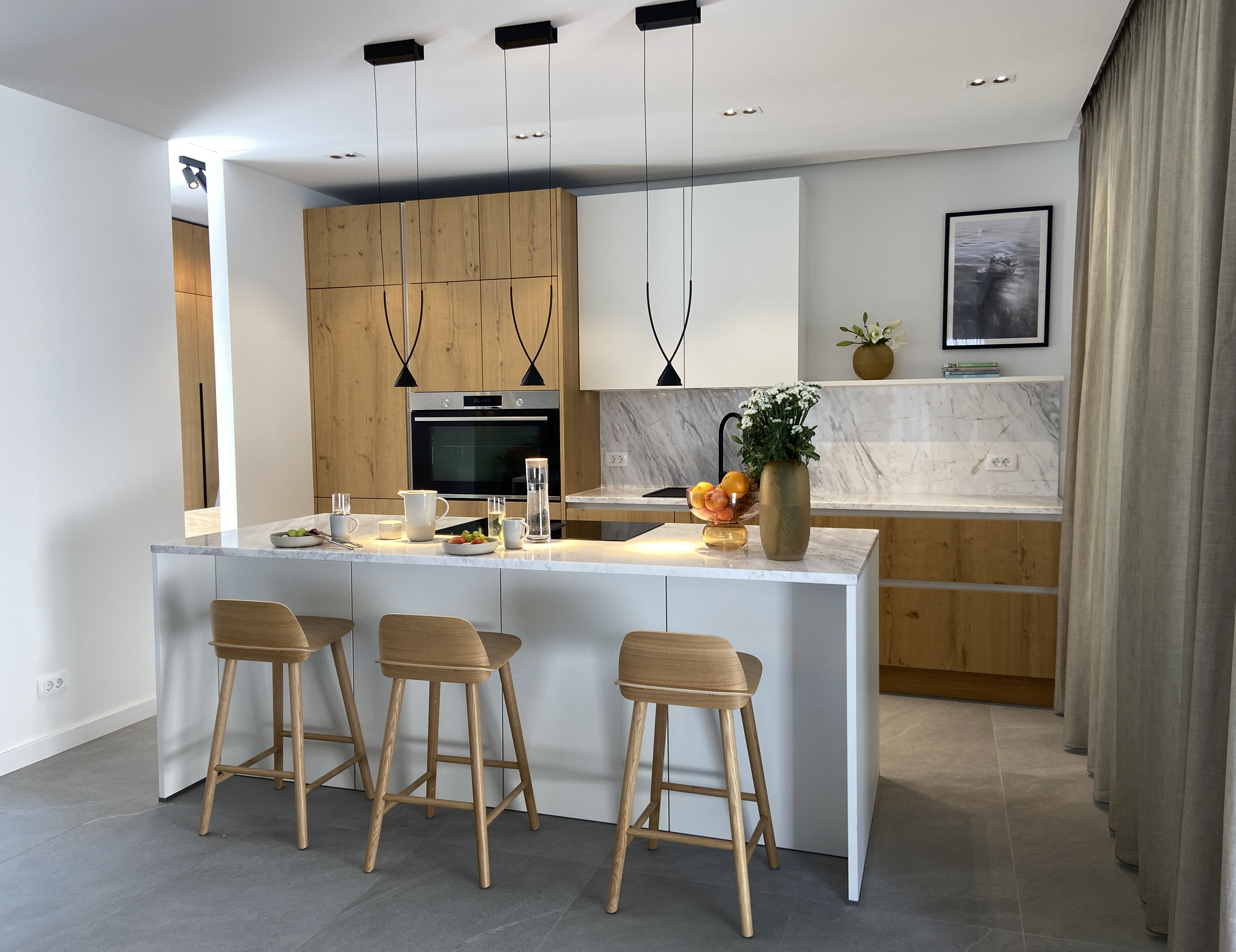 Kitchen — marble island, oak cabinetry, statement pendants