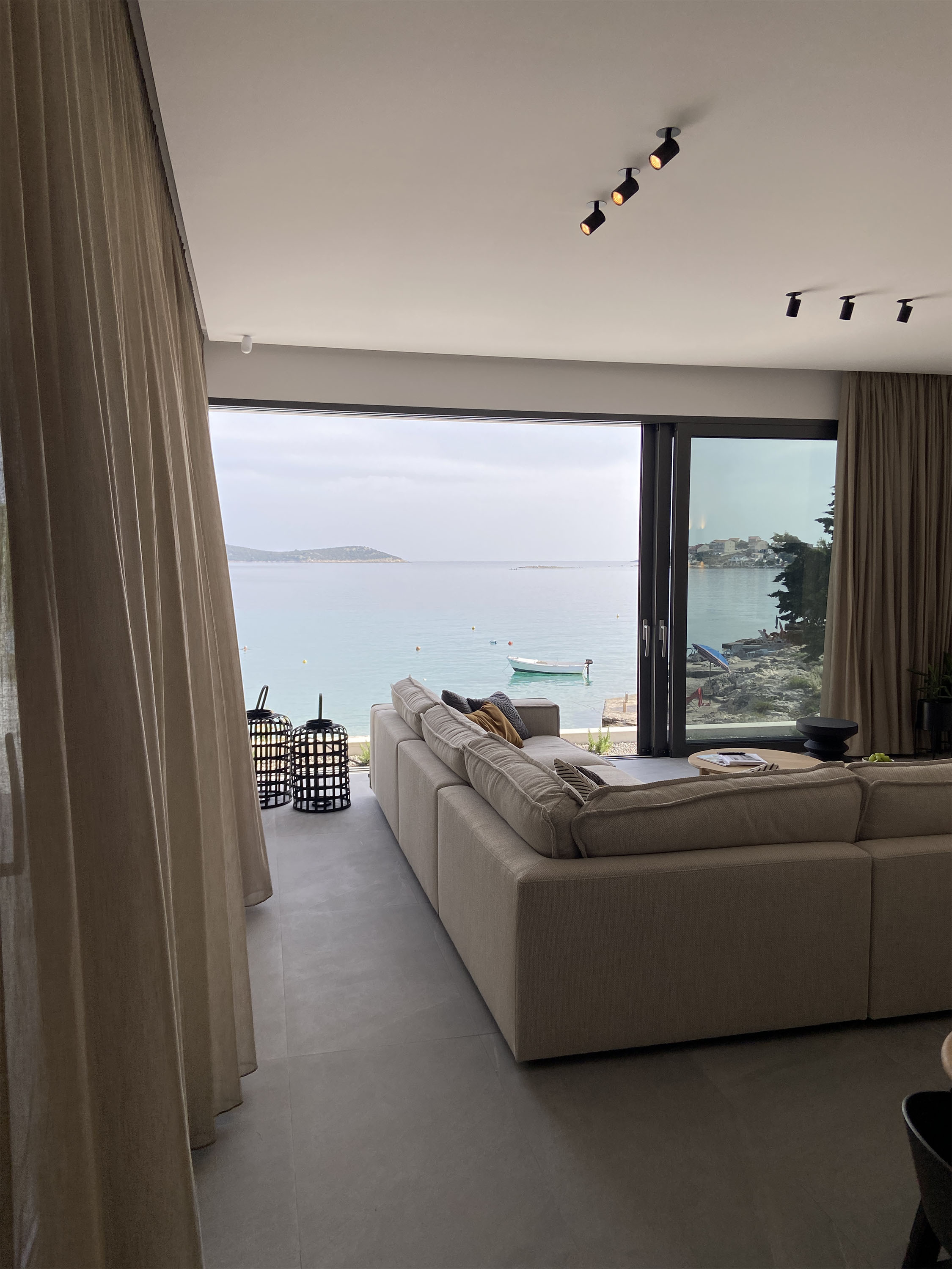 Living room fully open to the Adriatic — linen curtains, modular sofa