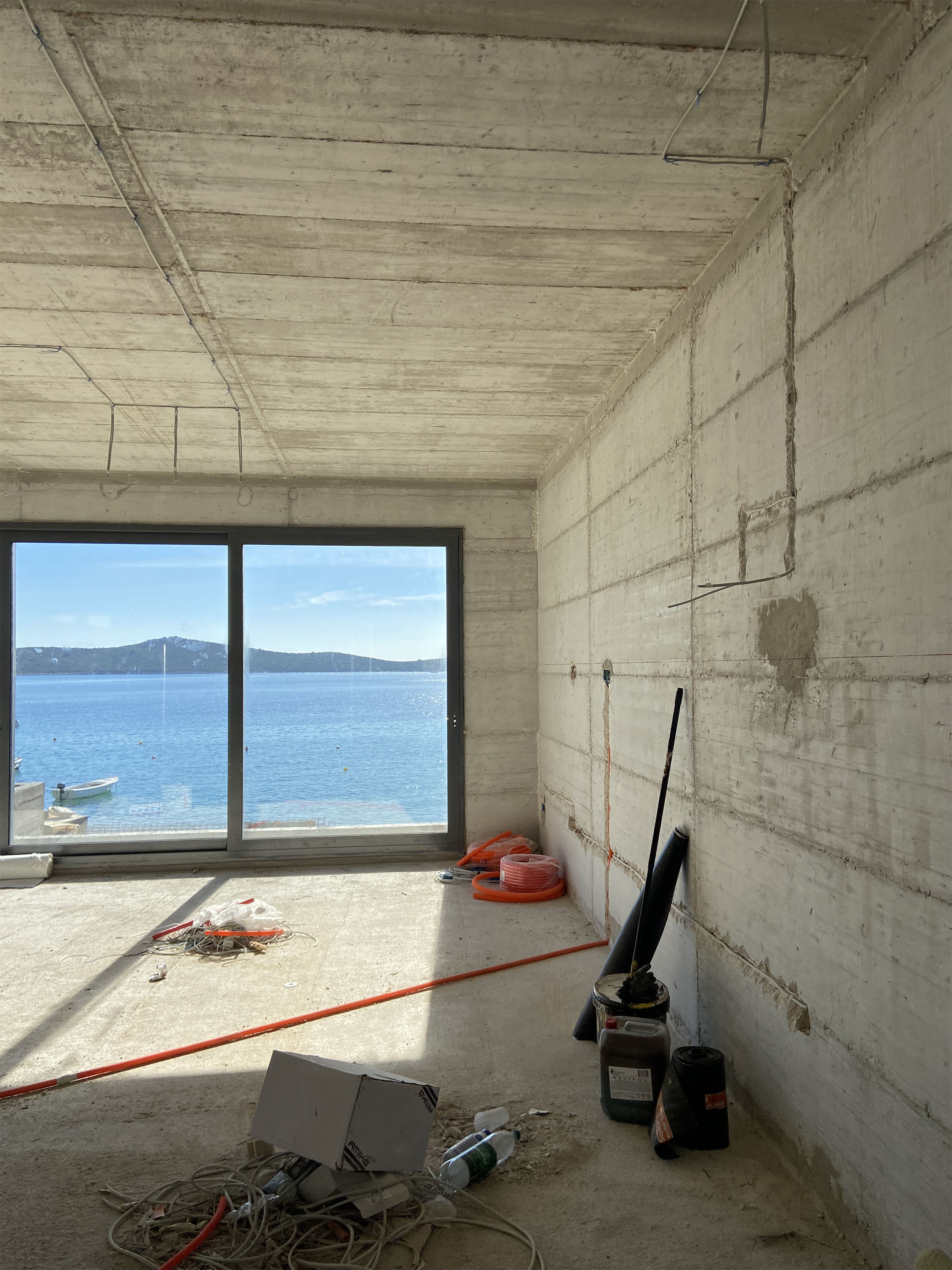 Living room during construction — raw concrete shell with sea view